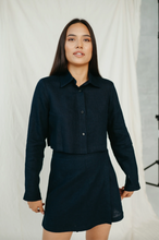 Load image into Gallery viewer, Model in a dark linen crop top showcasing its style, featuring a collared design and long sleeves with a trendy skirt.