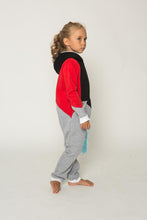 Load image into Gallery viewer, Sofa Killer tricolor unisex kids onesie Racing, featuring a red sleeve, black top, and light grey bottom. Child model shown in a side profile with bare feet, wearing a cozy onesie perfect for family nights.