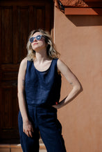 Load image into Gallery viewer, Model wearing the Dark Blue Linen Crop Top NOA by Sofa Killer, paired with matching linen trousers, enjoying a sunny day against a warm-toned wall.