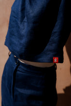 Load image into Gallery viewer, Close-up of the Sofa Killer dark blue linen trousers Lucia featuring the signature red tag, highlighting the soft texture of the fabric.