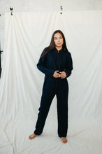 Load image into Gallery viewer, A model in a dark navy linen Sofa Killer women onesie, demonstrating a stylish and cozy appearance.
