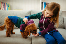 Load image into Gallery viewer, Sofa Killer tricolor unisex kids onesie Groove, with a child playfully dressing a puppy in a matching onesie, demonstrating the fun and versatility of the cozy outfit.