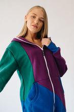 Load image into Gallery viewer, Model wearing the Sofa Killer tricolor onesie Groove, posing with a casual vibe, displaying the rich colors of dark green, royal blue, and violet.