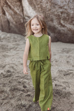 Load image into Gallery viewer, A happy girl wearing the Sofa Killer linen moss green set, featuring a stylish top and trousers, joyfully walking on the beach. Ideal for special occasions and family photos.