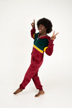Load image into Gallery viewer, Model wearing the Sofa Killer women velour onesie California in bordo, showing a fun pose while smiling and giving peace signs, perfect for cozy days.
