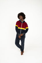 Load image into Gallery viewer, Sofa Killer women velour onesie Kansas in dark grey, red, and yellow worn by a model, showcasing its comfy design perfect for lazy days and outdoor fun.