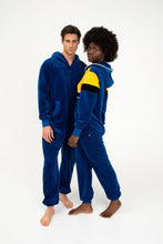 Load image into Gallery viewer, Couple in matching Sofa Killer women velour onesie Dakota, featuring royal blue and yellow design, showcasing a fun and relaxed vibe together.