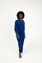 Load image into Gallery viewer, Model walking confidently in a Sofa Killer royal blue velour onesie Nevada, showcasing comfort and style.