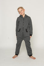 Load image into Gallery viewer, Sofa Killer dark grey unisex kids onesie with zipper in the back, model posing playfully with a smile, highlighting the comfortable fit and style.
