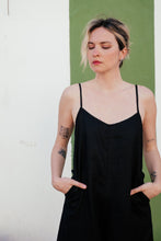 Load image into Gallery viewer, Close-up of a woman in the Women's Black Linen Jumpsuit Vega, hands in pockets, featuring a soft V-neckline and elegant, breathable fabric.

