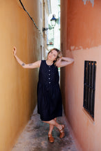Load image into Gallery viewer, Close-up of model in the Women's dark blue linen sleeveless dress Costa Blanca by SofaKiller, posing in a narrow alley with a stylish relaxed look.
