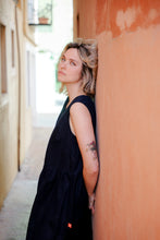 Load image into Gallery viewer, Model wearing the Women's dark blue linen sleeveless dress Costa Blanca by SofaKiller, leaning against a wall, exuding casual elegance.
