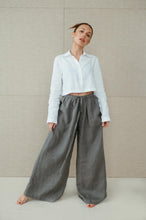 Load image into Gallery viewer, Woman wearing Sofa Killer natural green linen trousers in a relaxed pose, showcasing wide leg design and comfortable fit.
