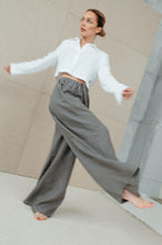 Load image into Gallery viewer, Dynamic shot of a woman in Sofa Killer natural green linen trousers, spinning with a flowing motion, emphasizing the wide leg style.
