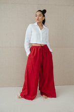 Load image into Gallery viewer, Sofa Killer red linen trousers Doha worn with a white crop button-up shirt, emphasizing a trendy wide leg design.
