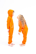 Load image into Gallery viewer, Sofa Killer orange unisex kids onesie with white cuffs, featuring two children standing face to face, showcasing the cozy design and playful style.

