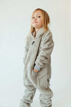 Load image into Gallery viewer, A girl confidently posing in a light grey Sofa Killer unisex bamboo onesie, showcasing its comfy fit and stylish look against a simple backdrop.
