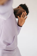 Load image into Gallery viewer, Close-up image of a model wearing the Sofa Killer men hoodie Medusa in light violet, playfully posing with a hand gesture.
