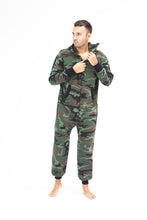 Load image into Gallery viewer, Sofa Killer men onesie with camouflage pattern CAMO, featuring a model standing and adjusting the zipper of the onesie, showcasing its stylish camouflage design.
