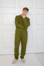 Load image into Gallery viewer, Sofa Killer dark green linen men onesie modeled by an individual with a thoughtful pose, demonstrating its casual yet chic style.
