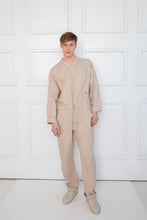 Load image into Gallery viewer, Model in a light beige linen men onesie by Sofa Killer, showcasing a comfortable and stylish summer outfit.
