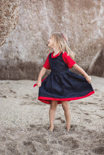 Load image into Gallery viewer, Girl twirling in the Sofa Killer linen dark blue dress with red details, enjoying a day at the beach.
