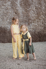 Load image into Gallery viewer, Two young girls playing on a beach, one wearing a Sofa Killer linen dark green dress with yellow color details, showcasing a playful summer vibe.
