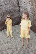 Load image into Gallery viewer, Two kids wearing Sofa Killer yellow color unisex kids onesie, smiling and playing in a sandy area.
