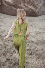 Load image into Gallery viewer, Back view of a girl in the Sofa Killer linen moss green girl set, showing the stylish design and lightweight fabric as she walks along the beach.
