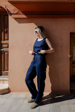 Load image into Gallery viewer, Close-up of a model adjusting the waistband of Sofa Killer dark blue linen trousers Lucia, showcasing the pants' relaxed fit and style.
