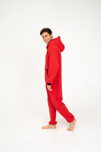 Load image into Gallery viewer, Side view of a young man in a Sofa Killer red onesie with black zipper, demonstrating its comfortable fit and stylish look.
