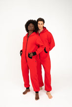 Load image into Gallery viewer, A young man and woman posing in matching Sofa Killer red onesies with black zippers, highlighting the trendy design.
