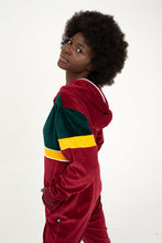 Load image into Gallery viewer, Sofa Killer women velour onesie California in bordo, green, and yellow, showcasing a model posing sideways with a stylish afro hairstyle.
