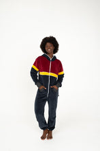 Load image into Gallery viewer, Sofa Killer women velour onesie Kansas displayed by a model with an afro hairstyle, featuring a stylish color block design, ideal for festivals and casual outings.
