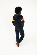 Load image into Gallery viewer, Back view of a model in the Sofa Killer women velour onesie Kansas, highlighting the cozy dark grey fabric and colorful striped sleeves.
