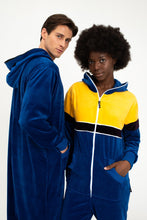 Load image into Gallery viewer, Close-up of two models in the Sofa Killer men velour onesie Dakota, showcasing the soft fabric and hood detail, with vibrant colors including royal blue and yellow.
