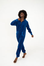 Load image into Gallery viewer, Sofa Killer women royal blue velour onesie Nevada being worn by a woman with an afro, walking confidently and smiling.
