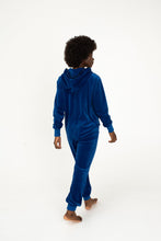 Load image into Gallery viewer, Back view of a woman wearing the Sofa Killer royal blue velour onesie Nevada, highlighting its comfortable fit and cozy design.
