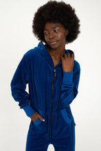 Load image into Gallery viewer, Woman wearing Sofa Killer royal blue velour onesie Nevada, looking stylish with a relaxed pose.
